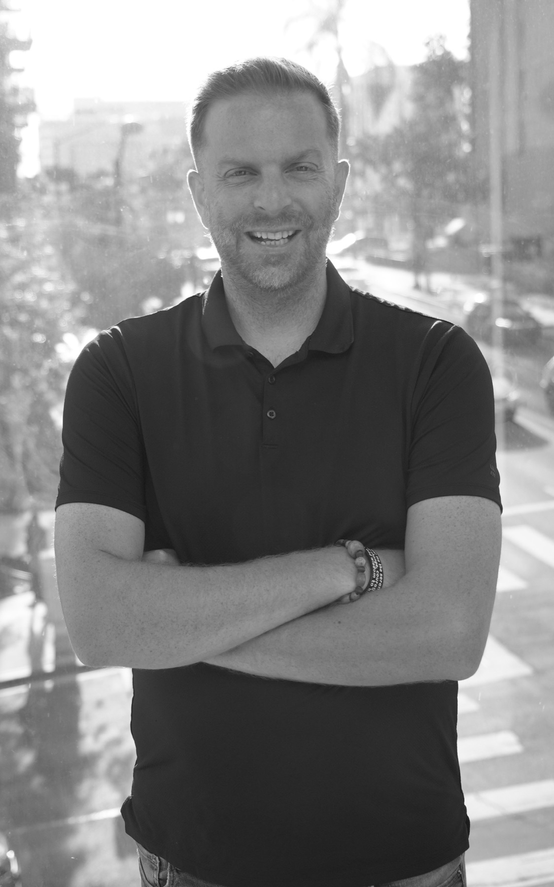 Black-and-white portrait of Michael Fanter smiling beside a sunlit window