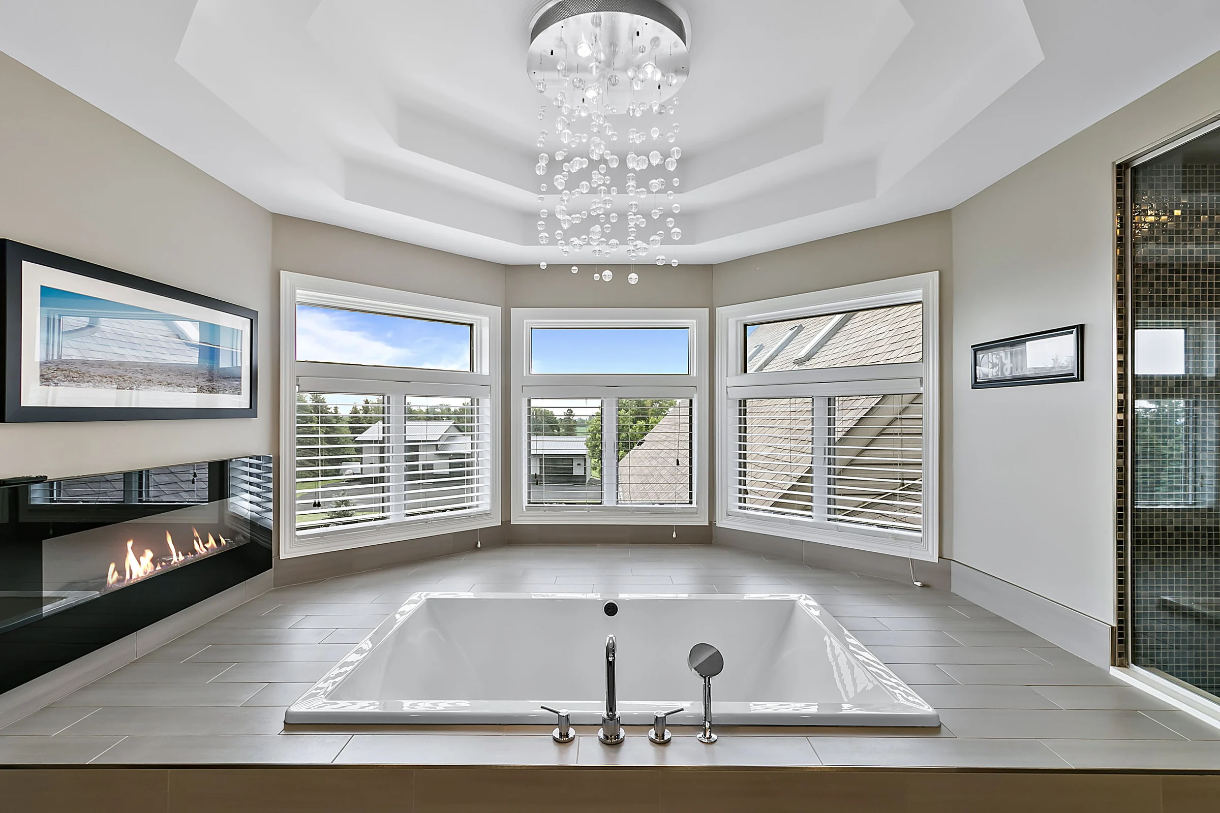 Bright bathroom with freestanding tub, fireplace, and chandelier
