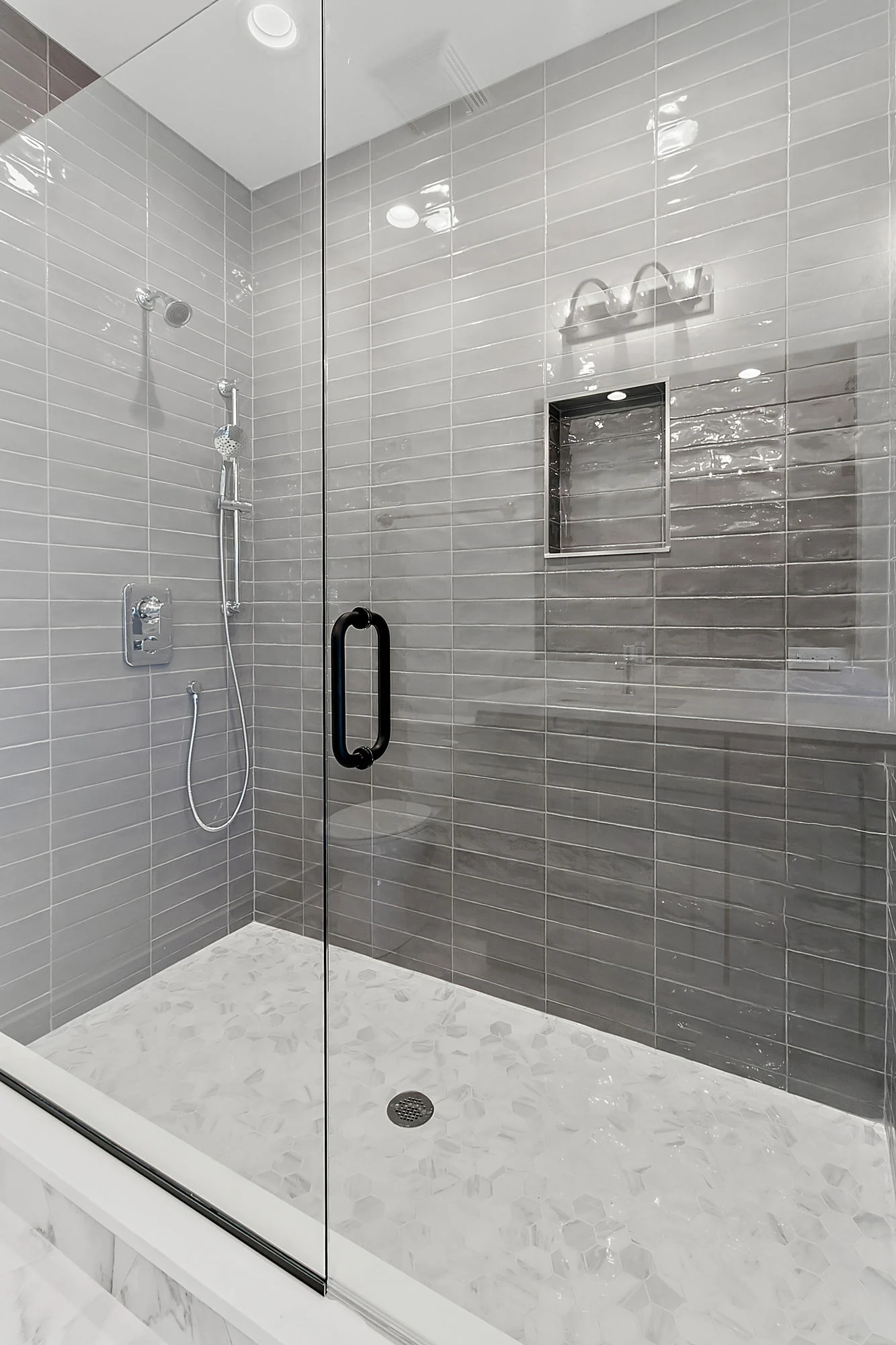 Glass shower enclosure with gray tile