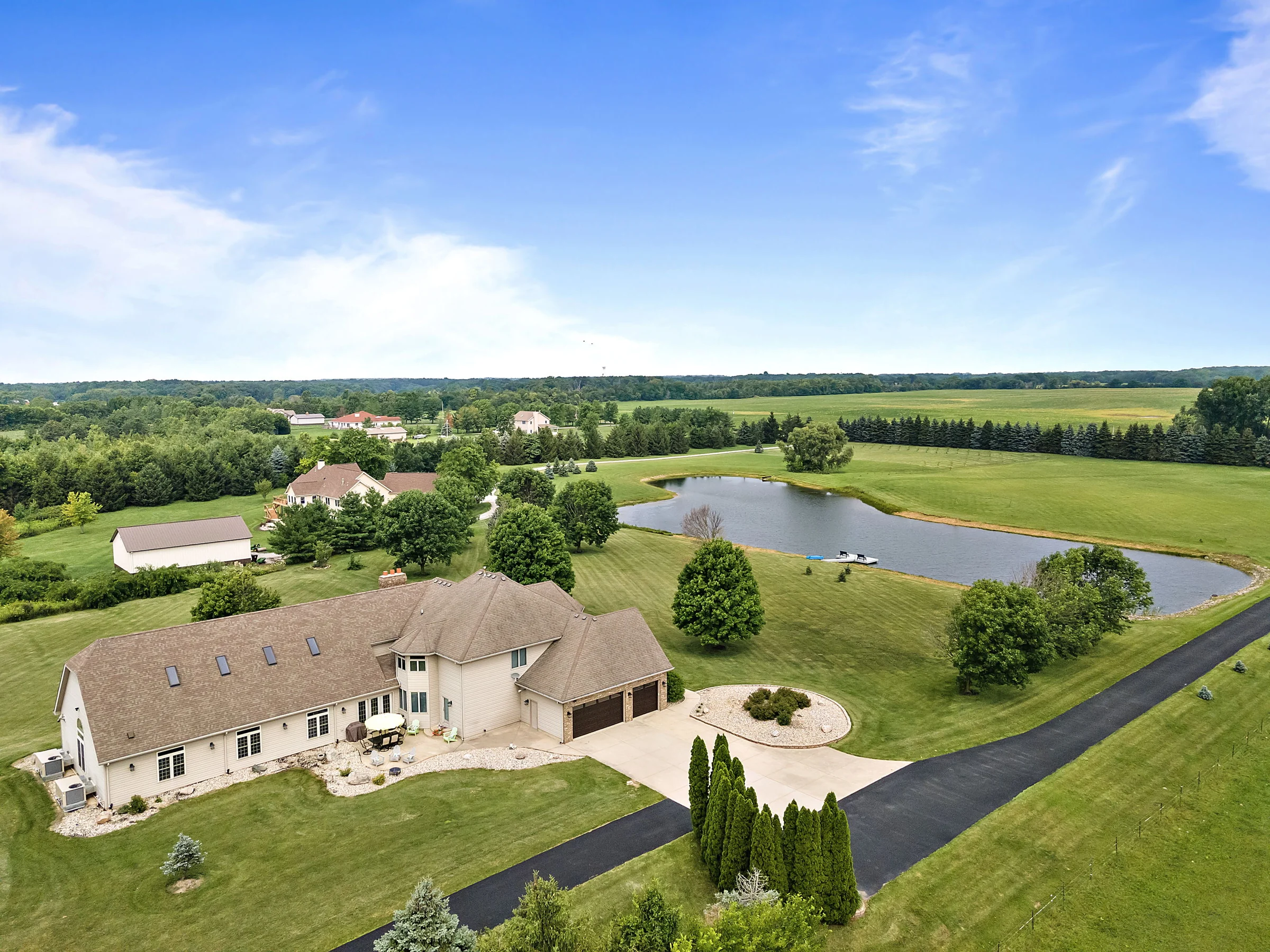 Aerial view of a home, grounds, and nearby pond