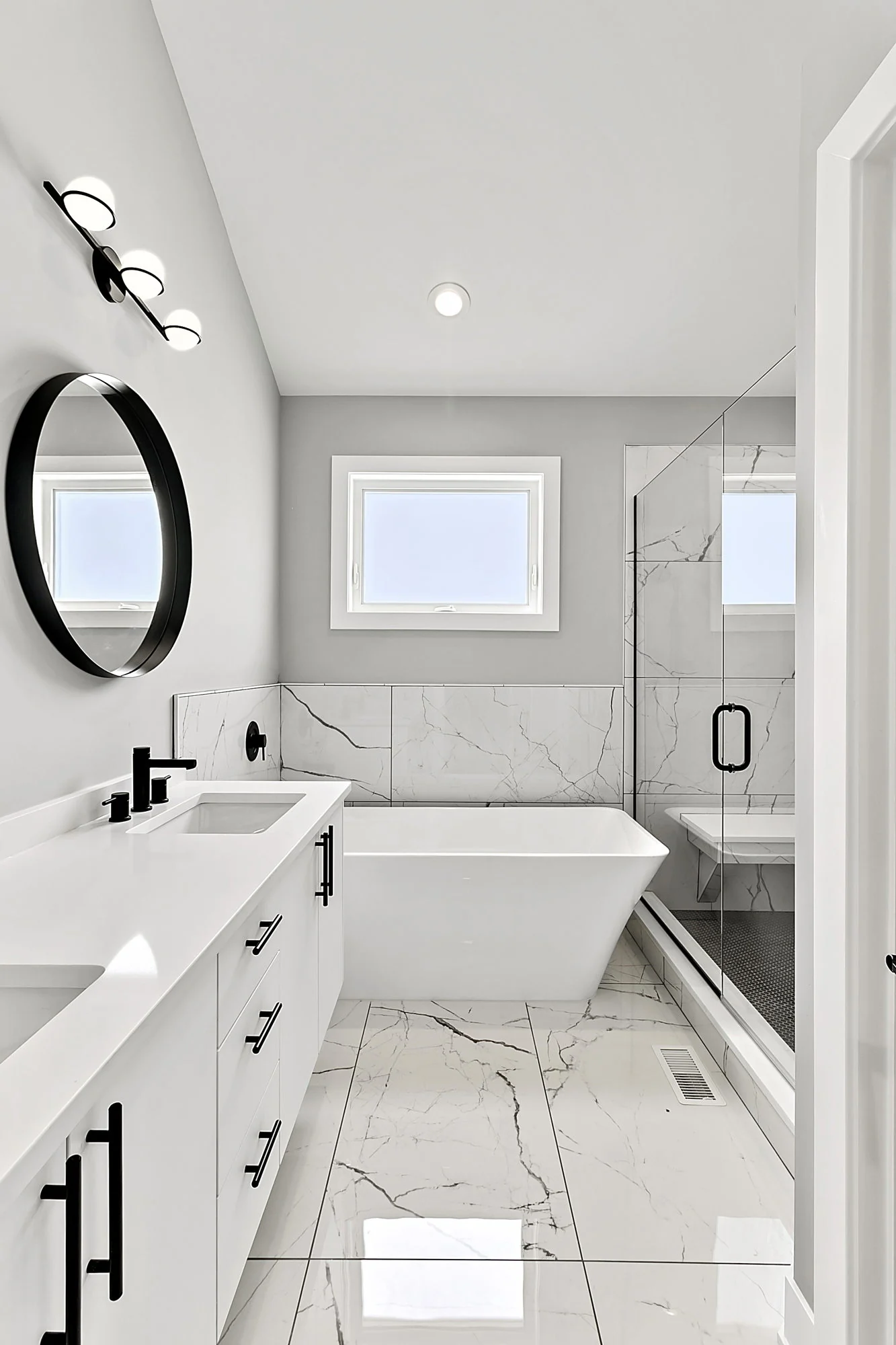 White bathroom with a tub, vanity, and marble-patterned surfaces